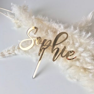 Pu&ograve; includere: Topper per torta in acrilico a specchio dorato con il nome "Sophie" scritto in corsivo.