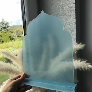 May include: A light blue frosted acrylic arch with a decorative top and a base. The arch has the text "101 Creative" printed on it.