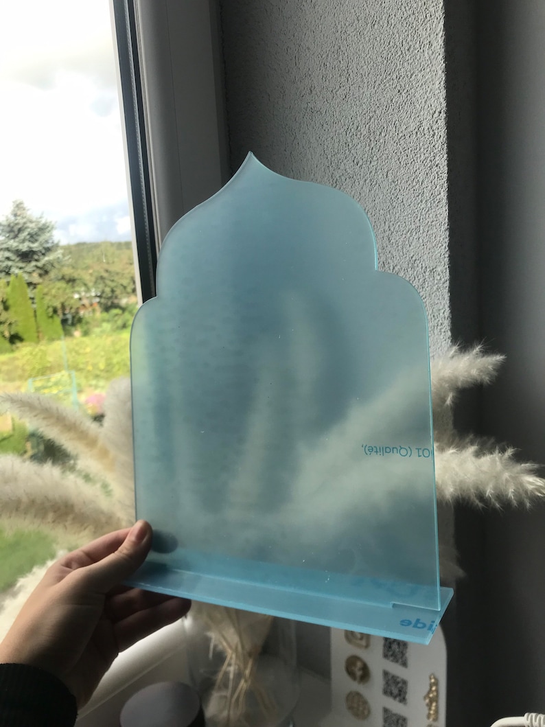 May include: A light blue frosted acrylic arch with a decorative top and a base. The arch has the text "101 Creative" printed on it.