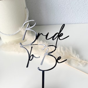 Könnte beinhalten: Schwarzer Acryl-Kuchentopper mit den Worten "Bride to Be" in kursiv.
