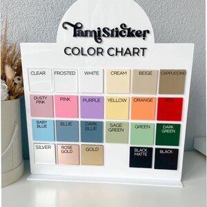 Op de afbeelding: Een witte acryl kleurenkaart display met de tekst "TamiSticker COLOR CHART". De kaart toont een raster van kleurstalen in verschillende tinten, waaronder helder, mat, wit, cr&egrave;me, beige en cappuccino.