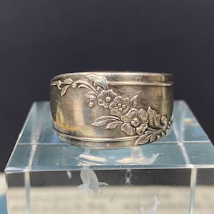 May include: Silver ring made from a repurposed spoon with a floral design.