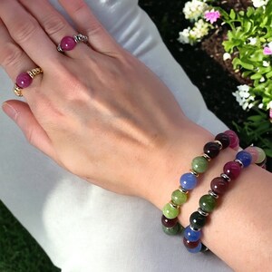 May include: Two bracelets with colorful round beads. One bracelet has green, blue, and purple beads. The other bracelet has green, red, and blue beads.