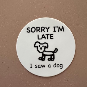 May include: White round sticker with black text that reads "Sorry I'm Late I saw a dog". A simple black and white cartoon dog is drawn in the center of the sticker.