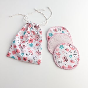 May include: Set of three reusable makeup remover pads with a floral print and pink trim, in a white drawstring bag with a floral print.
