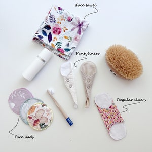 Könnte beinhalten: Eine Sammlung von Zero-Waste-Essentials von KOKO, darunter ein florales Handtuch, wiederverwendbare Wattepads, eine Bambuszahnbürste, Slipeinlagen, normale Einlagen und eine Naturborstenbürste.