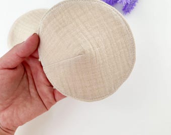 May include: Two beige reusable breast pads made of soft fabric.