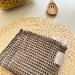 In this photo are caramel color kitchen towel laying on lunch table.