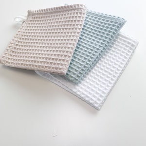 May include: Three waffle weave kitchen towels in beige, light blue, and white.