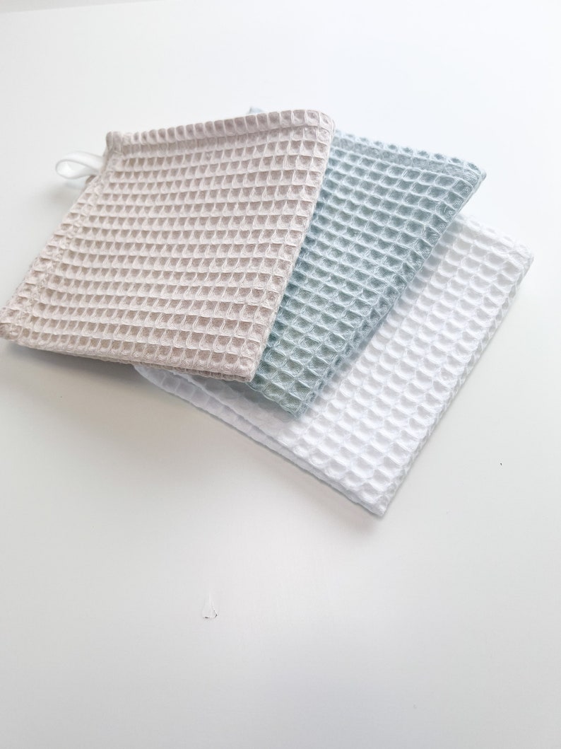 May include: Three waffle weave kitchen towels in beige, light blue, and white.