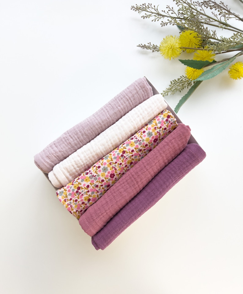 Peut inclure: Un lot de cinq langes en mousseline douce pour b&eacute;b&eacute;, dans une vari&eacute;t&eacute; de couleurs, dont le rose, le violet et le blanc avec un imprim&eacute; floral. Les langes sont pli&eacute;s et dispos&eacute;s dans une bo&icirc;te.