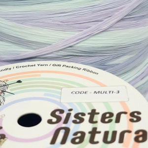 Può includere: Primo piano di una bobina di filato per uncinetto multicolore con il testo "Sisters Natura". Il filato è una miscela di colori pastello, tra cui lavanda, blu e verde menta. L'etichetta recita "CODE - MULTI-3".