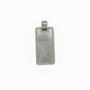 Puede incluir: Pendiente rectangular de plata con un bucle de plata en la parte superior. El pendiente tiene el texto "4 GRAMS 925 Breda" grabado en la parte posterior.