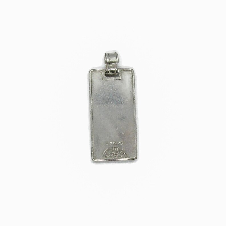 Puede incluir: Pendiente rectangular de plata con un bucle de plata en la parte superior. El pendiente tiene el texto "4 GRAMS 925 Breda" grabado en la parte posterior.