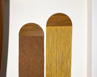 May include: Two wall hangings with wooden half-circle tops and long, flowing strands of yarn. The left hanging has brown yarn and the right hanging has yellow yarn.
