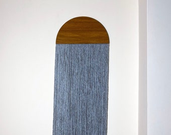May include: A gray yarn wall hanging with a wooden half-circle at the top.