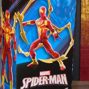 Pu&ograve; includere: Action figure di Iron Spider Marvel Legends in scatola. La figura &egrave; rossa e gialla con molteplici zampe di ragno meccaniche. La scatola presenta il logo Marvel Spider-Man e un'avvertenza per le piccole parti.