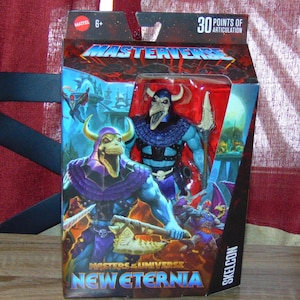 Puede incluir: Una figura de acción de Skeletor de Masters of the Universe: New Eternia, una figura esquelética azul y morada con un casco con cuernos y un arma. La figura está empaquetada en una caja con un fondo rojo y las palabras "Masters of the Universe: New Eternia" y "Skeletor" impresas en ella.