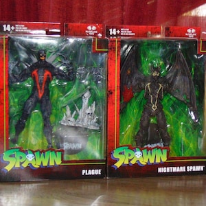 May include: Two action figures of Spawn, a comic book character. The figure on the left is Plague Spawn, a black and red figure with a green background. The figure on the right is Nightmare Spawn, a black figure with wings and a green background. Both figures are packaged in clear plastic boxes with the Spawn logo and the character's name.