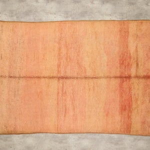 Può includere: Un grande tappeto rettangolare, tessuto in color arancio e marrone con un sottile motivo a righe. Il tappeto ha un aspetto leggermente usurato, che gli conferisce un'atmosfera vintage.