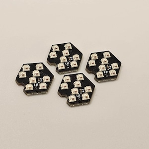 以下が含まれることがあります： 白いLEDライトが付いた黒い六角形の回路基板が4枚。各基板には、グリッドパターンに12個のライトが配置されています。