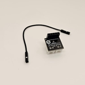 Könnte beinhalten: Eine schwarz-weiße Platine mit dem Text "www.twiddle.fi/hardware" und "SSR Mini 12V Thermistor Rev 3". Die Platine hat einen schwarzen Header mit sechs Pins und ein schwarzes Kabel mit zwei Steckern.