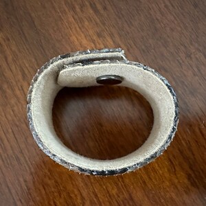 May include: A brown and black snakeskin bracelet with a magnetic clasp.