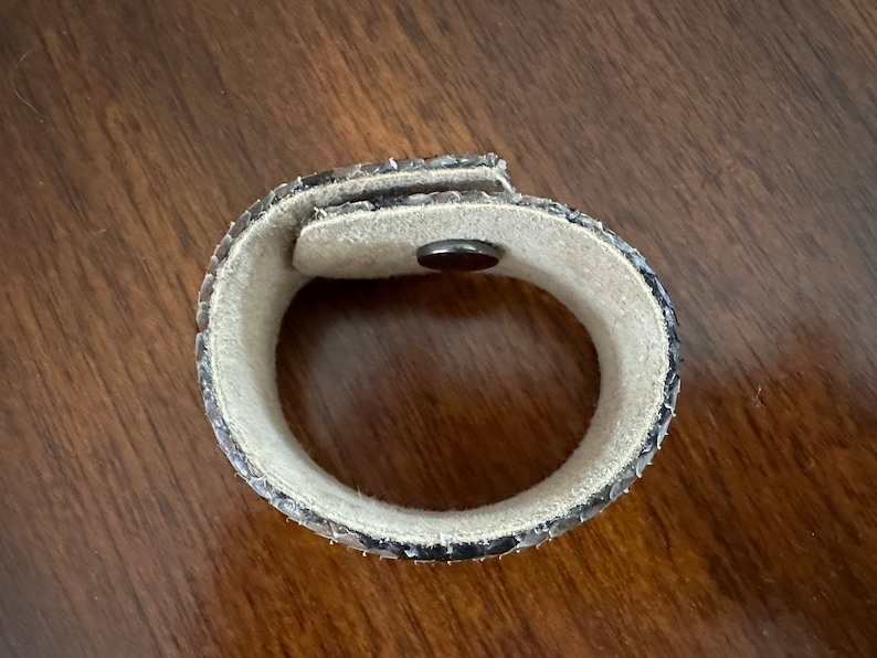 May include: A brown and black snakeskin bracelet with a magnetic clasp.