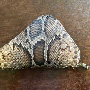 May include: A brown and gold snakeskin wallet with a zipper closure.