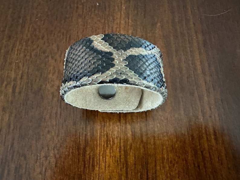 May include: A brown and black snakeskin bracelet with a magnetic clasp.