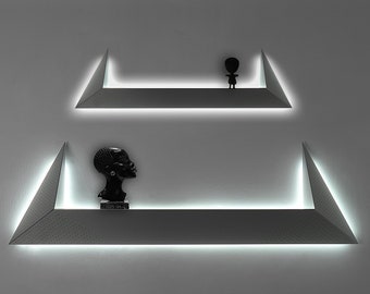 May include: Two triangular shelves with a white LED light strip along the edge. The top shelf has a small black figurine on it. The bottom shelf has a black bust sculpture on it.
