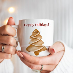 May include: White ceramic mug with a brown gingerbread tree design and the text "Happy Holidays!" in red.