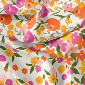 K&ouml;nnte beinhalten: Ein wei&szlig;er Stoff mit einem Blumenmuster. Die Blumen sind rosa, orange und gelb. Der Stoff ist in der Mitte gefaltet, sodass das Muster auf beiden Seiten sichtbar ist.