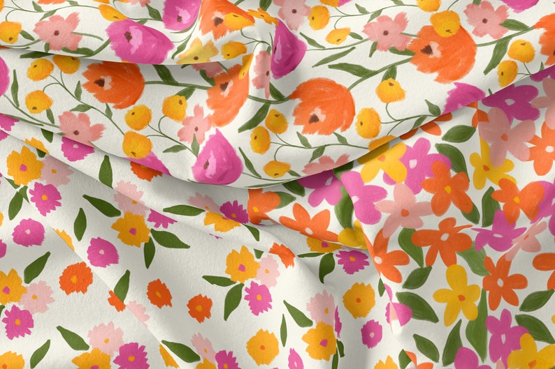 K&ouml;nnte beinhalten: Ein wei&szlig;er Stoff mit einem Blumenmuster. Die Blumen sind rosa, orange und gelb. Der Stoff ist in der Mitte gefaltet, sodass das Muster auf beiden Seiten sichtbar ist.