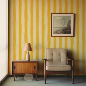 May include: A room with a yellow and white striped wall, a wooden side table, and a beige armchair. A lamp sits on the table, and a framed landscape painting hangs on the wall. The room has a mid-century modern style.