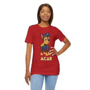May include: Red t-shirt featuring a cartoon dog character in a police uniform. The dog is brown and tan with a blue hat and vest. The text "ACAB" is printed in yellow below the dog.