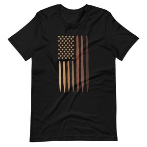 Op de afbeelding: Zwart T-shirt met een afbeelding van een Amerikaanse vlag met strepen in verschillende bruintinten die huidtinten voorstellen.