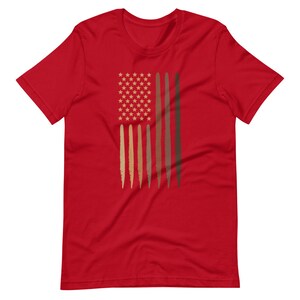 Op de afbeelding: Rood T-shirt met een afbeelding van een Amerikaanse vlag met bruine strepen die verschillende huidtinten voorstellen.