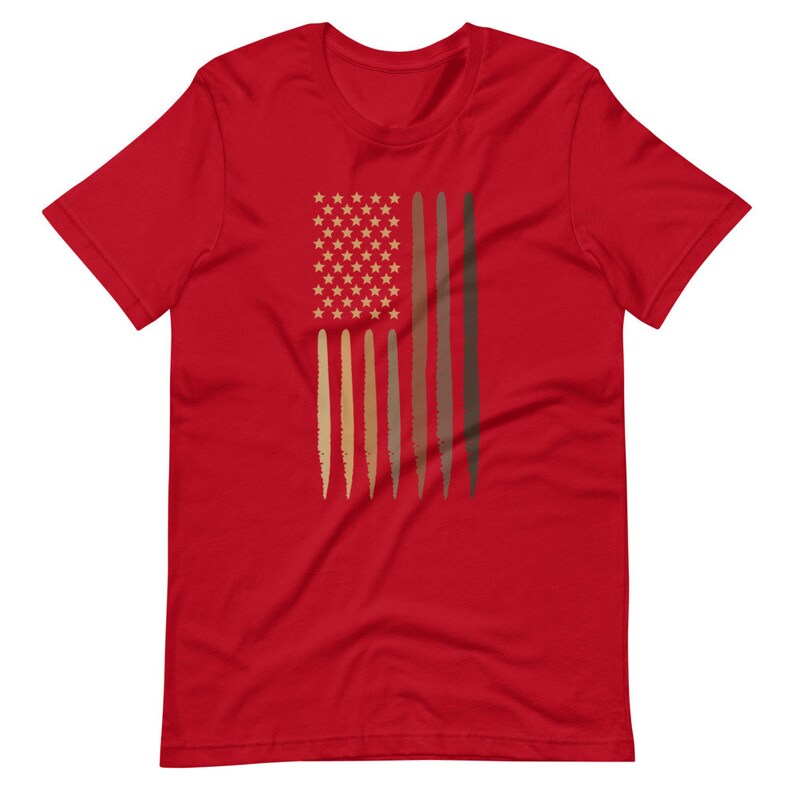 Op de afbeelding: Rood T-shirt met een afbeelding van een Amerikaanse vlag met bruine strepen die verschillende huidtinten voorstellen.