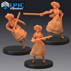 May include: Three miniature figures of women wearing hats and holding swords. The figures are painted in a light orange color and are standing on black bases.