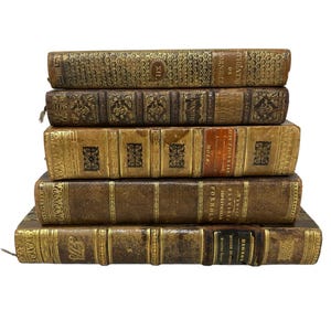 May include: A stack of six antique leather-bound books with gold accents and embossed details. The books are arranged in a vertical stack with the spines facing outward. The top book has the title "THEATRE DE CORNELIE" on the spine. The bottom book has the title "HISTOIRE DE FRANCE" on the spine.