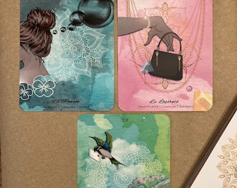 May include: Three rectangular oracle cards with rounded corners. Card 26 shows a person with a bun, a mandala, and bubbles. Card 25 features a hand holding a black handbag with gold chains. Card 27 depicts a bird carrying a letter near a stone structure.