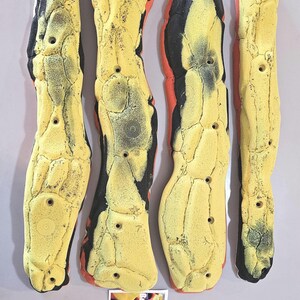 May include: Four yellow and black climbing holds with a textured surface and drilled holes. The holds have a unique, organic shape and are designed for rock climbing. A small card with the text "Barn Holds Climbing" is in the image.