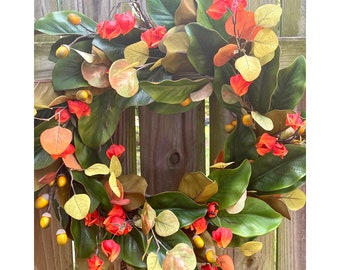 Magnolia leaves on fall wreath for front door. Autumn grapevine wreath with magnolia leaves, eucalyptus leaves, orange flowers and acorns