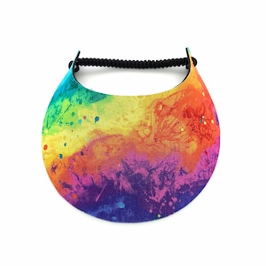 May include: A rainbow-coloured visor with a black elastic band. The visor has a splatter paint design with shades of yellow, orange, red, purple, and blue.
