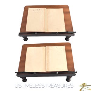 May include: Two wooden book stands with a dark brown finish. Each stand holds an open book with aged, cream-colored pages. The stands have a sloped design and are supported by four rounded legs. The text "USTIMELESSTREASURES" is at the bottom.