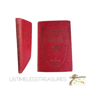 May include: A red hardcover book titled "Physical Culture Food Directory" by  "Maud Hastings". The book cover features a stylized image of a globe.