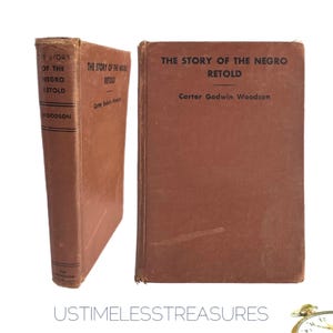 May include: Two brown hardcover books titled "THE STORY OF THE NEGRO RETOLD" by Carter Godwin Woodson. One book is standing upright, showing the spine with the title and author. The other book is lying flat, displaying the cover. The books are set against a white background.