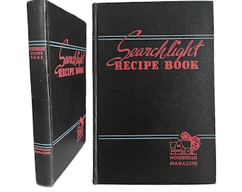 May include: Black vintage recipe book titled "Searchlight Recipe Book" with red lettering and a house logo. The book is from "Household Magazine". The book is displayed upright and on its side.