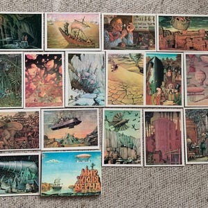 May include: A collection of vintage postcards featuring illustrations of fantastical scenes. The images depict submarines, airships, and other imaginative elements, with a color palette of greens, blues, and browns. The postcards are arranged on a textured surface.